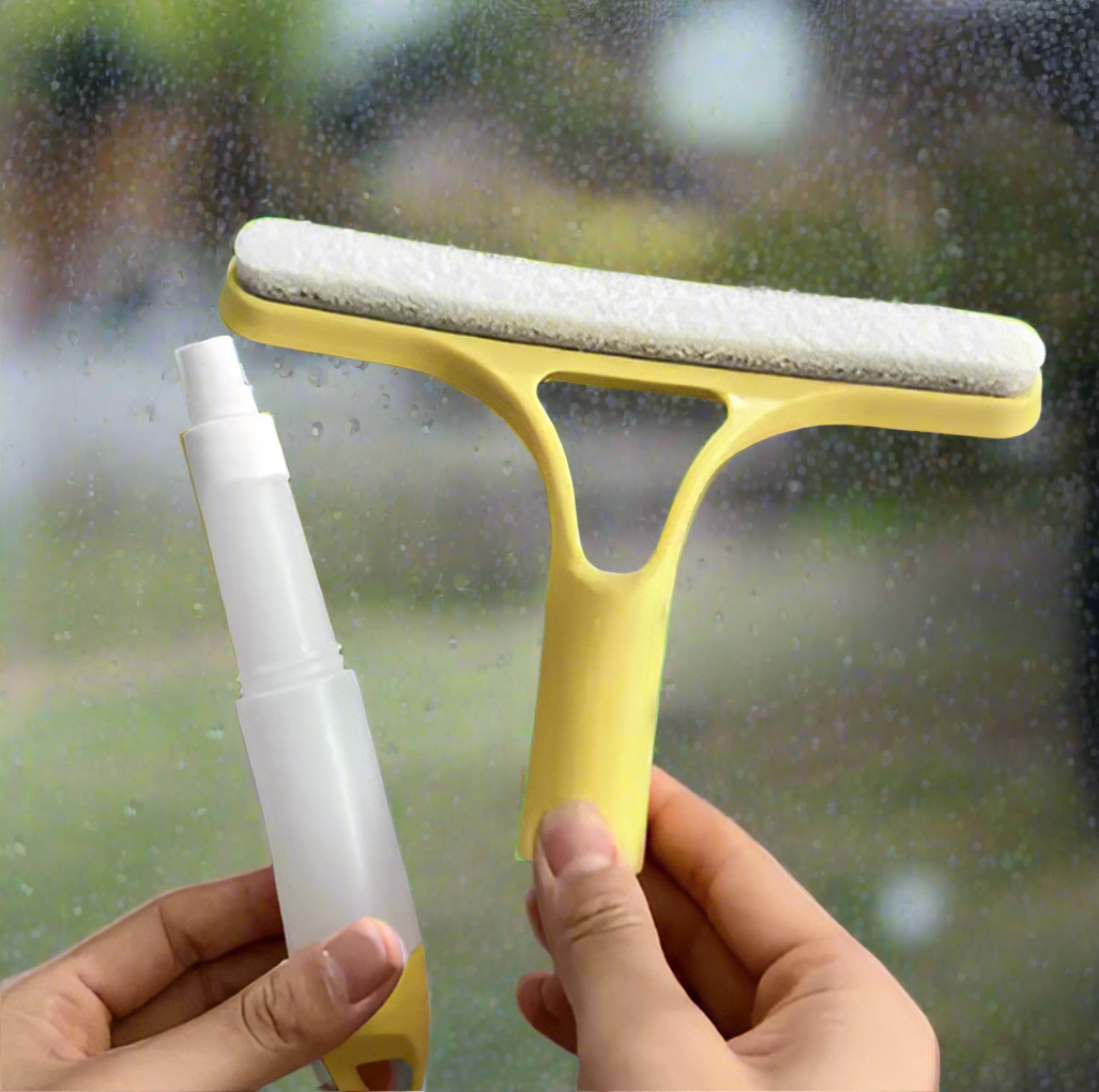 Mist spray bottle with squeegee held by a hand against a gray background